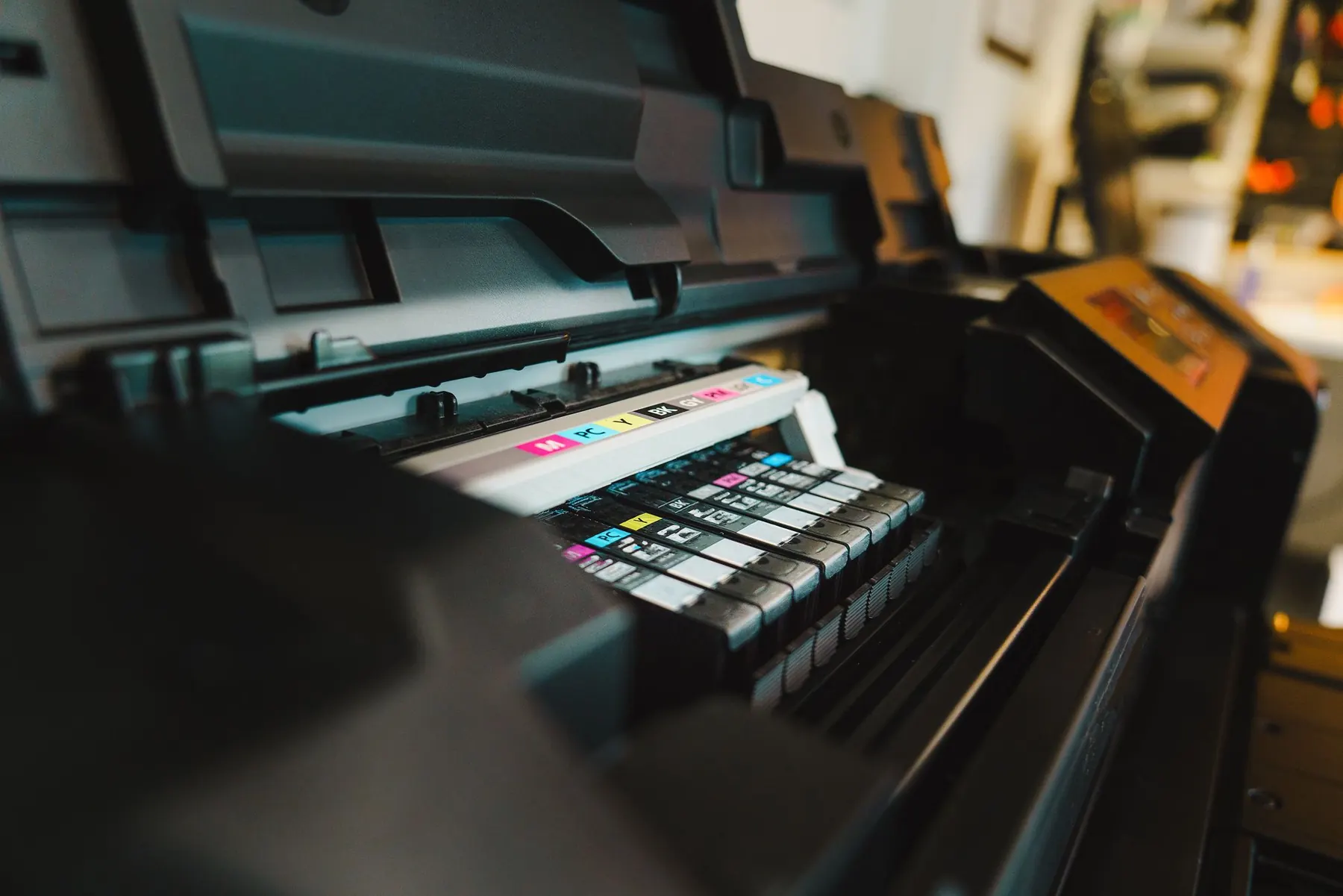 Close-up of a large-format inkjet printer carriage with colour ink cartridges