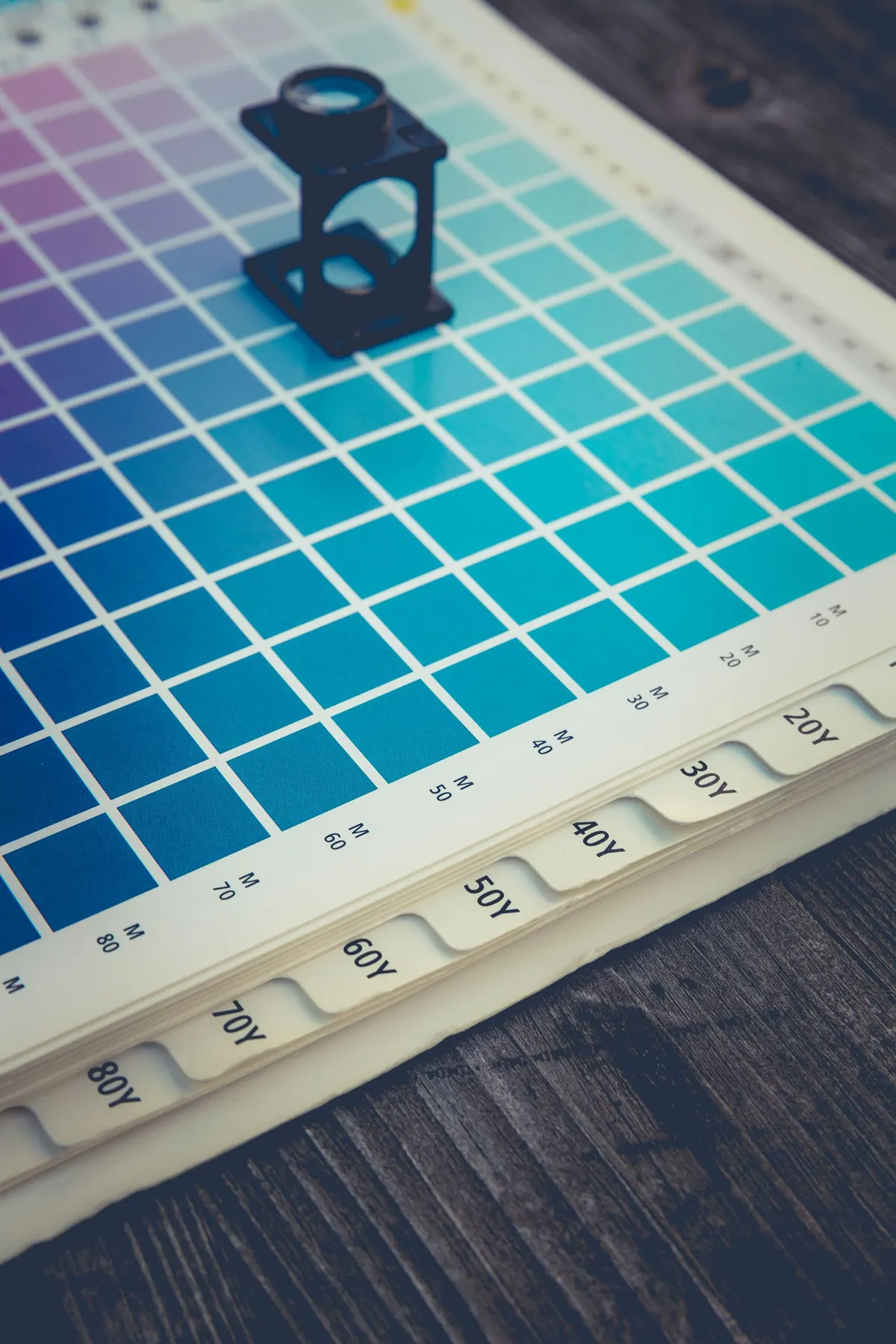 Printer's loupe resting on a cyan colour proof chart